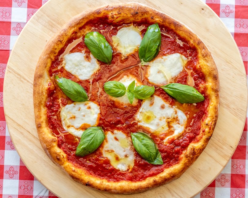 A freshly baked Margherita pizza with rich red sauce, melted mozzarella, and fresh basil leaves.
