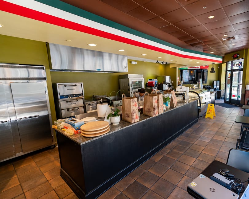 Interior of a Pizza Express restaurant with a counter, kitchen equipment, and a person working.